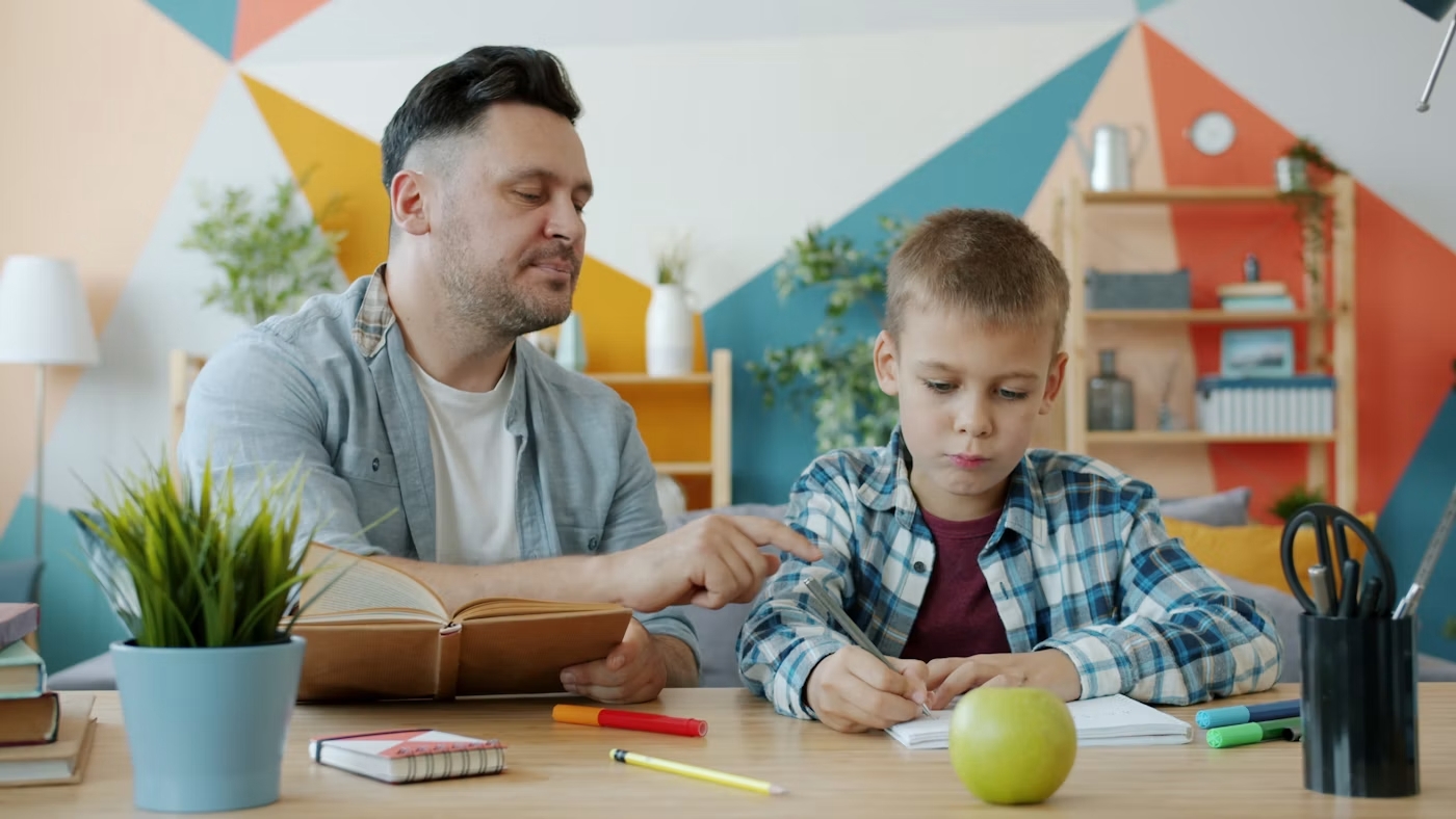 Father helping his son with reading and writing at home for age 5 learning